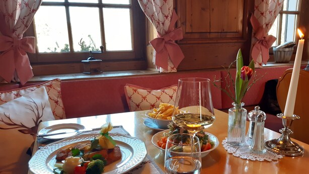 A dining table set with plates of food, glasses of wine, and candles.