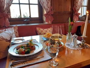 Une table à manger dressée avec des assiettes remplies de nourriture, des verres de vin et des bougies.