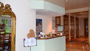 A reception area with a wooden reception desk, a large mirror, a colorful poster, and a computer monitor.