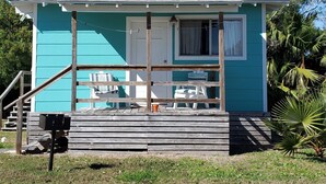 A small, single-story house with a porch, a wooden staircase, and a mailbox.