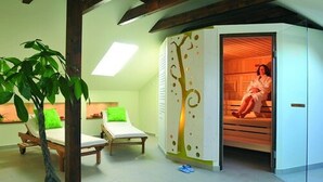Un cuarto de spa con un banco de madera, una planta verde y una persona relajándose en una cabaña de madera.