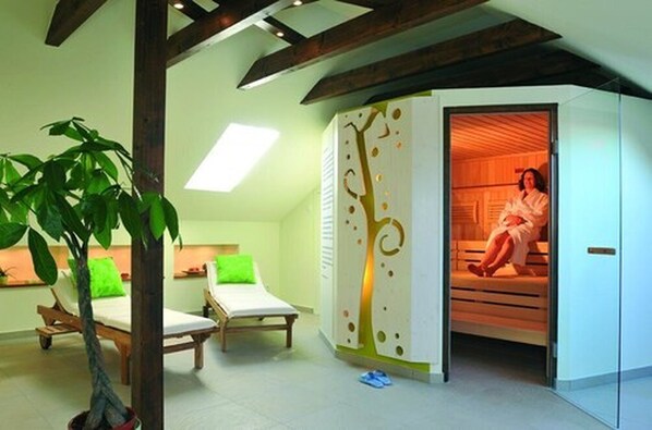 Un cuarto de spa con un banco de madera, una planta verde y una persona relajándose en una cabaña de madera.