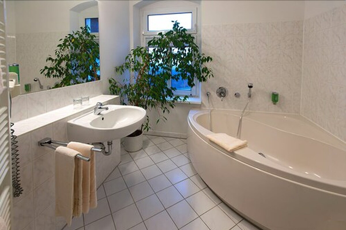 A modern bathroom with a bathtub, a sink, and two potted plants.