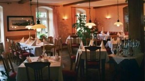 Un restaurante con varias mesas dispuestas para comer, con lámparas colgantes y un ambiente interior cálido.