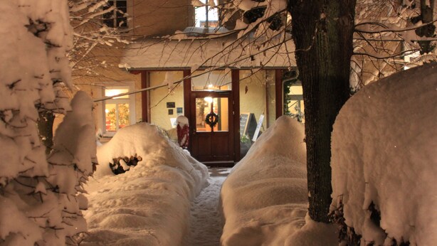 Un sendero cubierto de nieve que lleva a la entrada de un edificio con un adorno navideño en la puerta.