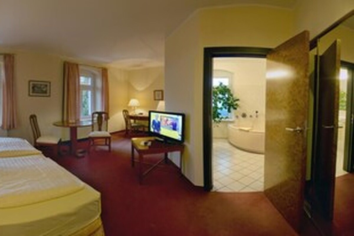 A hotel room with two beds, a television, a desk, and a bathroom.