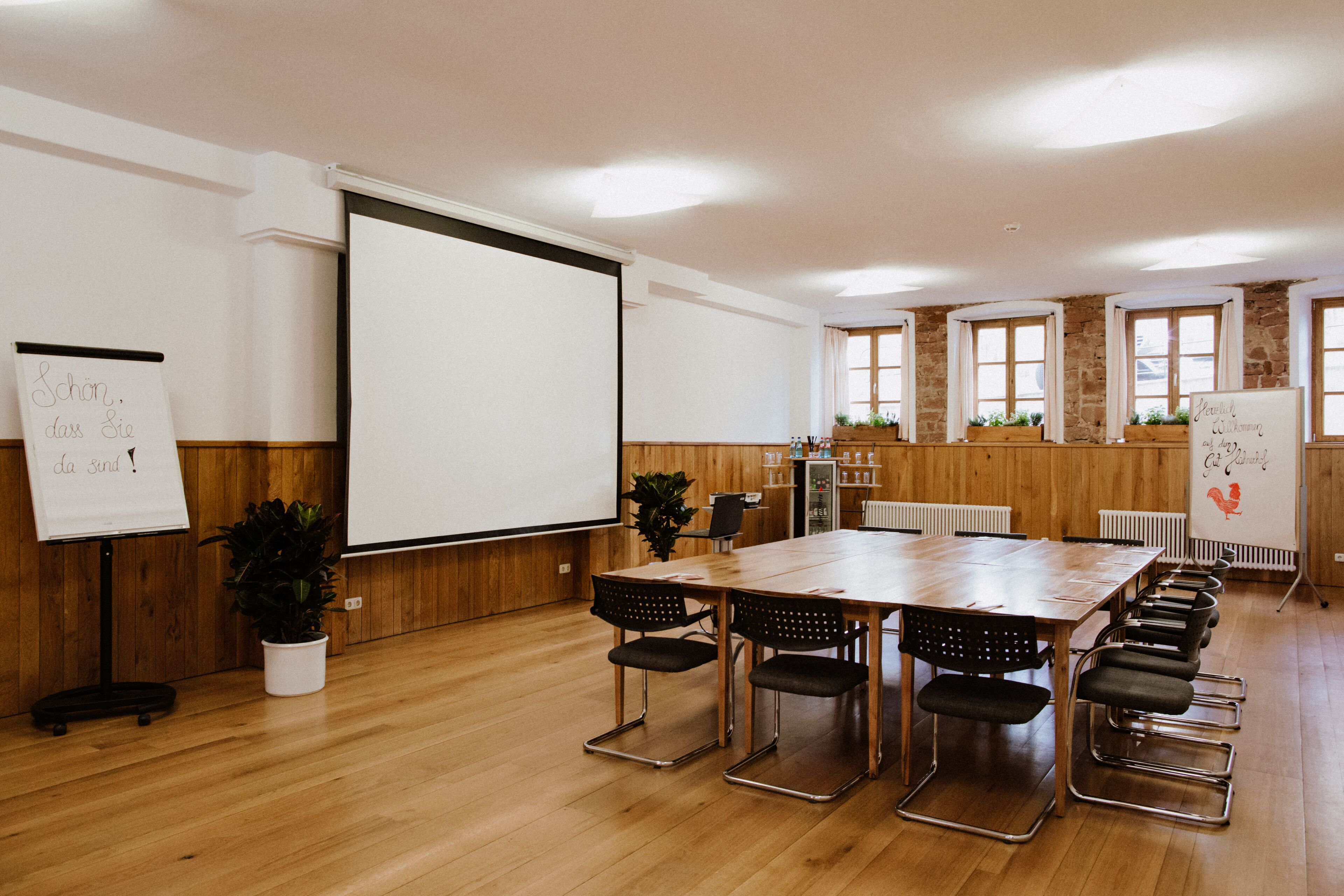Une salle de conférence équipée d’une longue table, de nombreuses chaises, d’un écran de projection et de tableaux blancs.