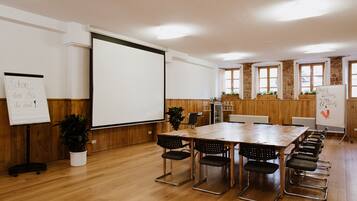 Une salle de conférence équipée d’une longue table, de nombreuses chaises, d’un écran de projection et de tableaux blancs.