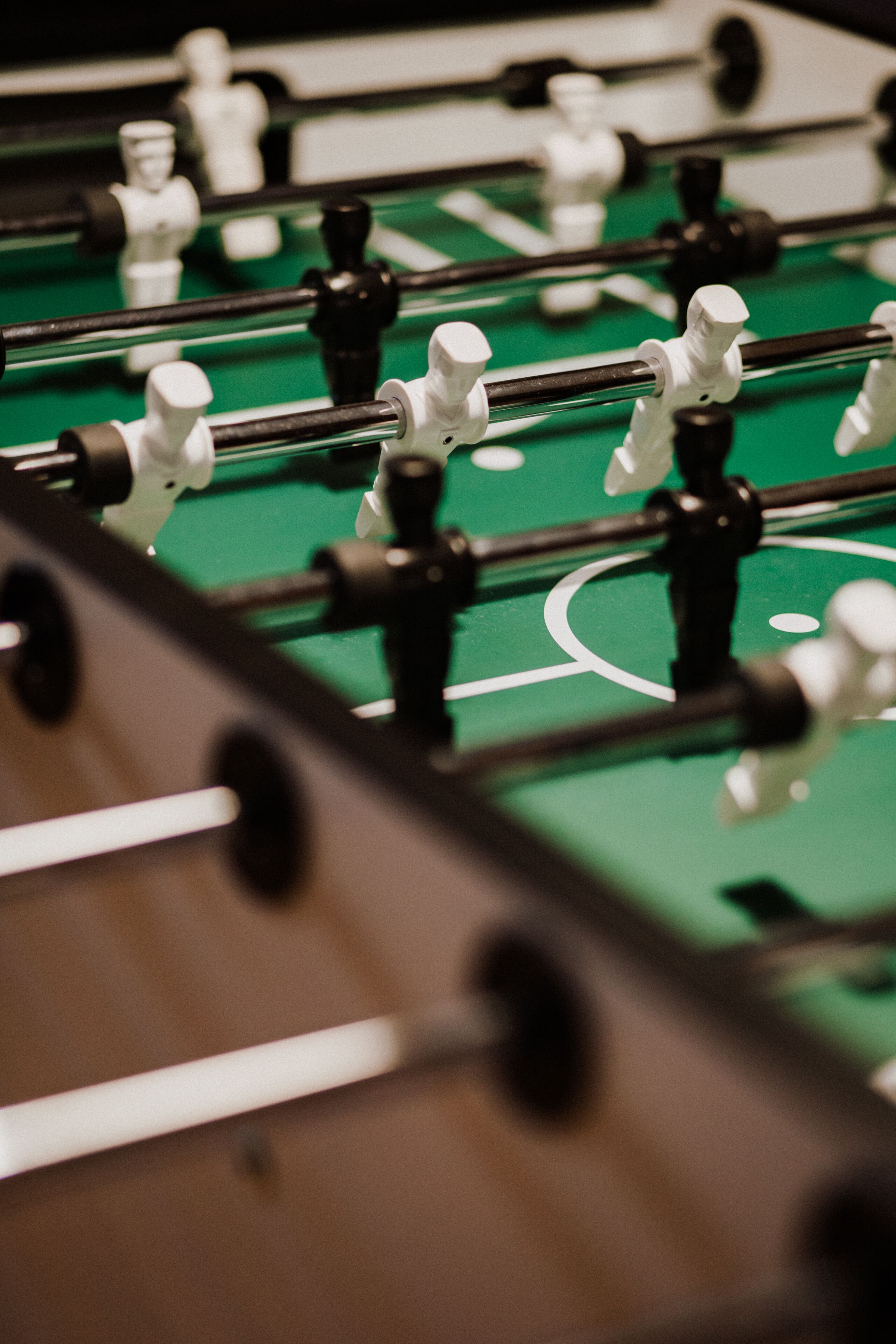 A close-up of a foosball table with a green playing surface and black and white player figures.