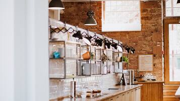 A kitchen with wooden cabinets, a brick wall, and hanging pendant lights.