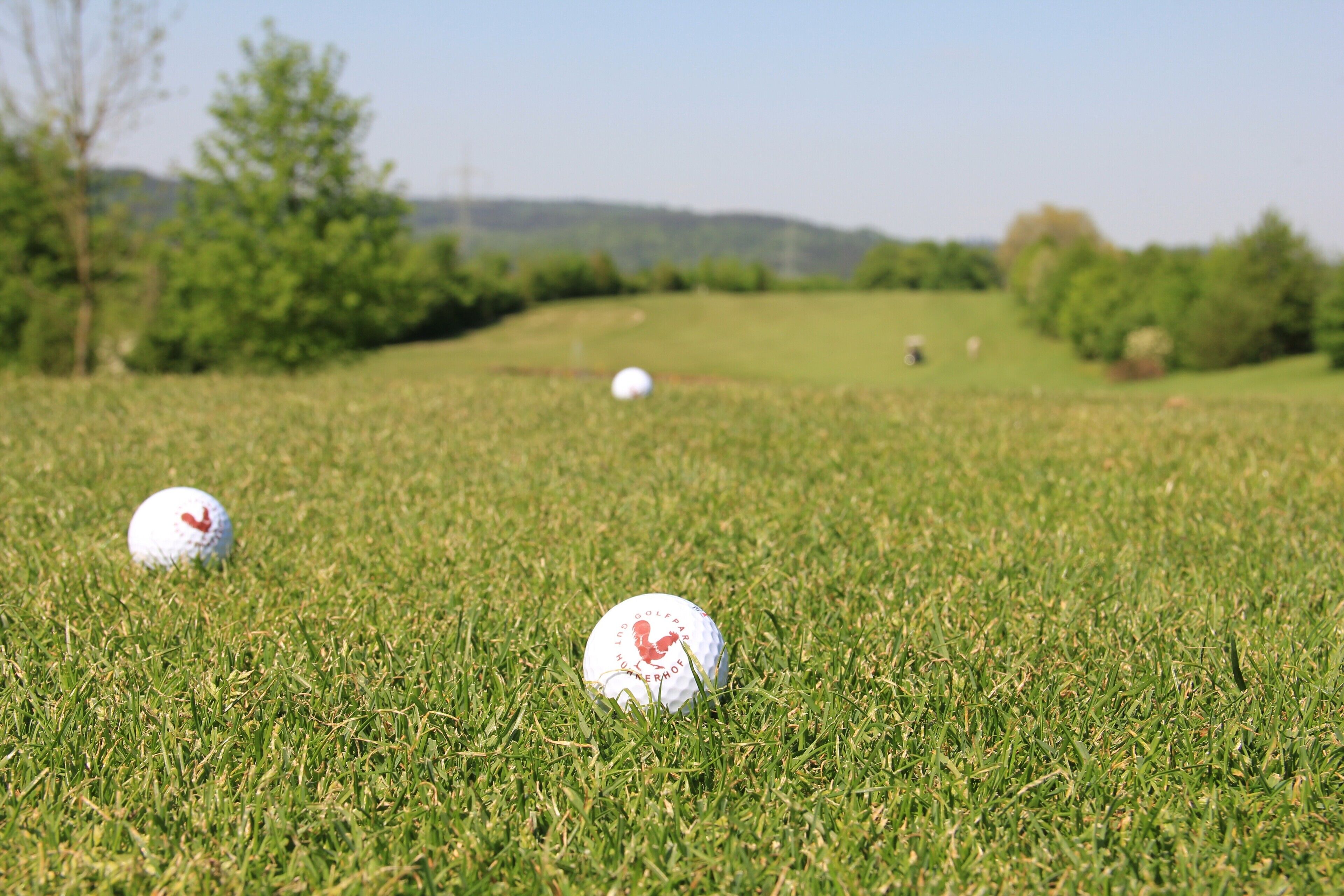 Ein Golfplatz mit drei Bällen auf dem Rasen.