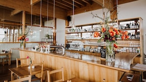 A wooden interior with a bar area, seating, and a coffee machine. - Hotel Gut Hühnerhof (Gruendau)