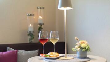 Une table avec deux verres à vin, un petit vase avec des fleurs et un chandelier en arrière-plan.