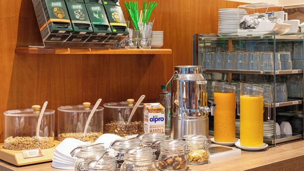 Un bufé de desayuno con diversas opciones de comida, una máquina de café y un dispensador de zumo.