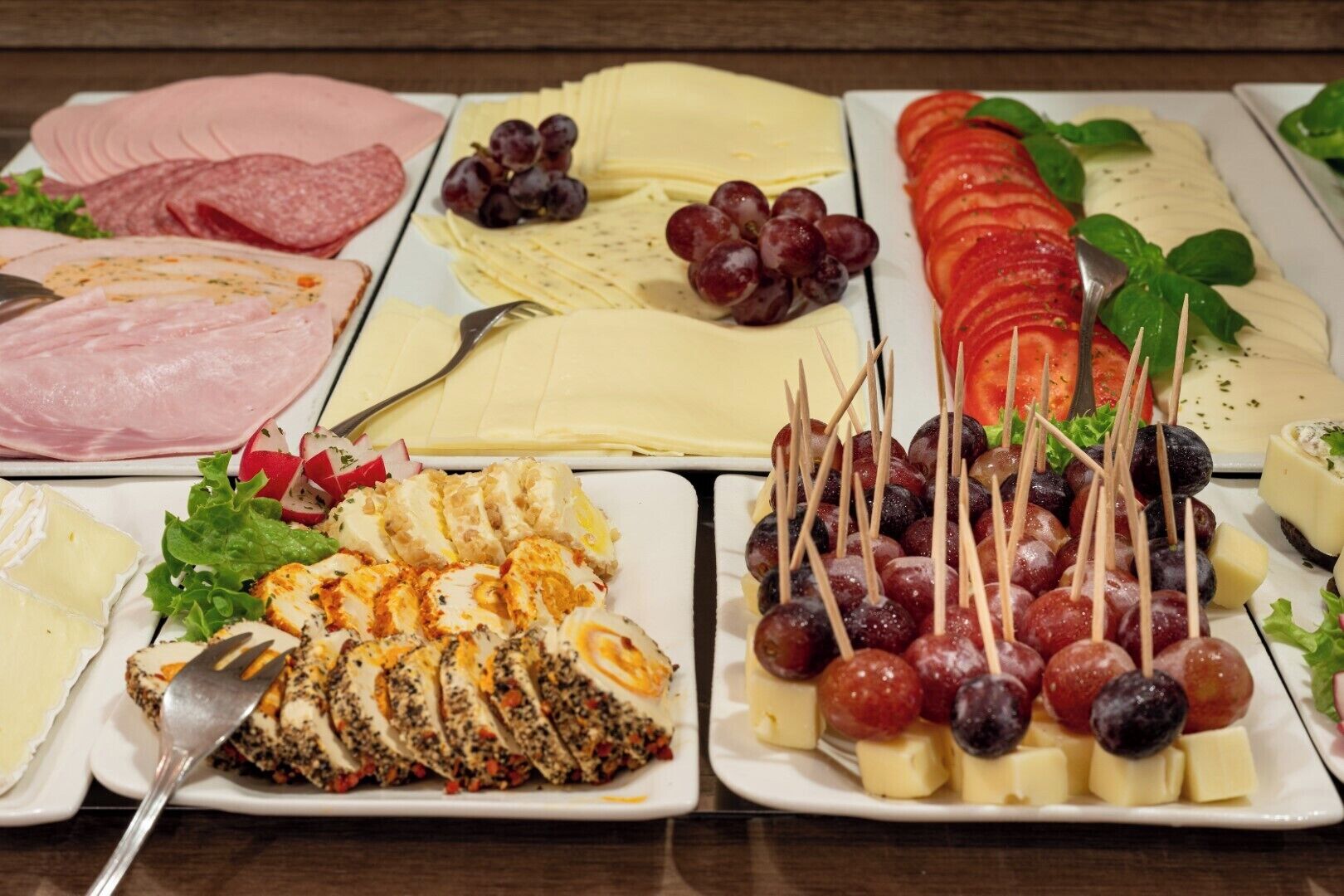 A variety of cheeses, meats, and fruits on a table.
