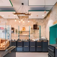 A modern kitchen with a marble backsplash, pendant lights, and a central island with black cabinets.