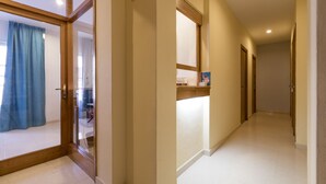 A hallway with a wooden door, a blue curtain, and a tiled floor. - Hostal Ferrer (Sant Antoni de Portmany)