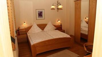 A bedroom with a wooden bed, two bedside lamps, a nightstand, a mirror, and a framed picture on the wall.