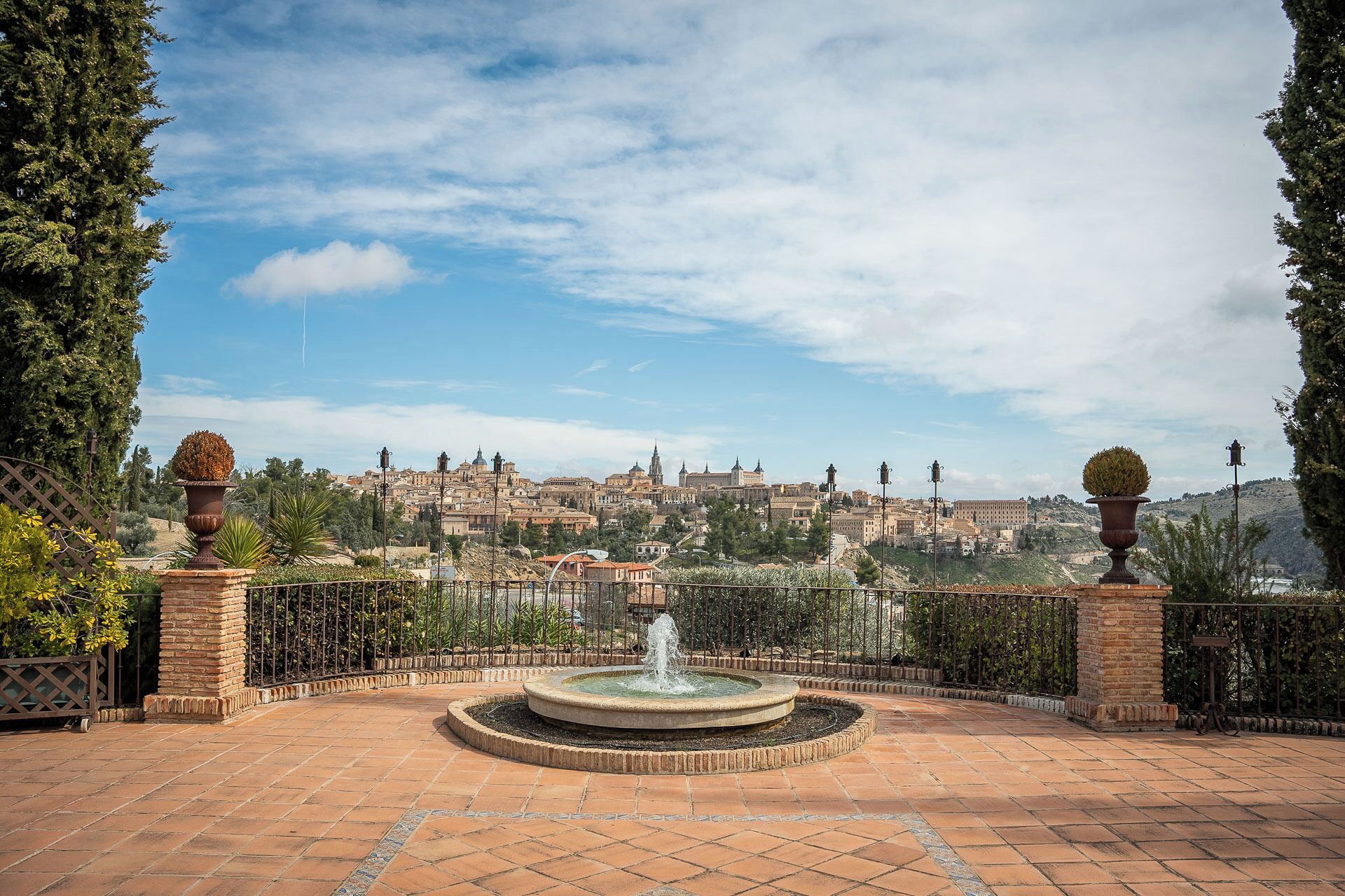 A courtyard with a fountain, surrounded by brick walls and potted plants.