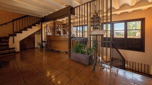 Un vestíbulo amplio con una escalera de madera, un mostrador de recepción y vistas al exterior.