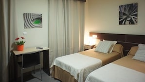 A hotel room with two beds, a desk, a chair, a lamp, and a painting on the wall. - Hotel MR (Tarragona)