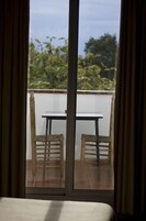 Una stanza con una porta vetrata scorrevole che si apre su un balcone esterno con un tavolo e due sedie.