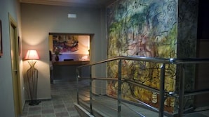 A staircase with metal railings leading to a room with a large abstract painting on the wall. - Hotel MR (Tarragona)