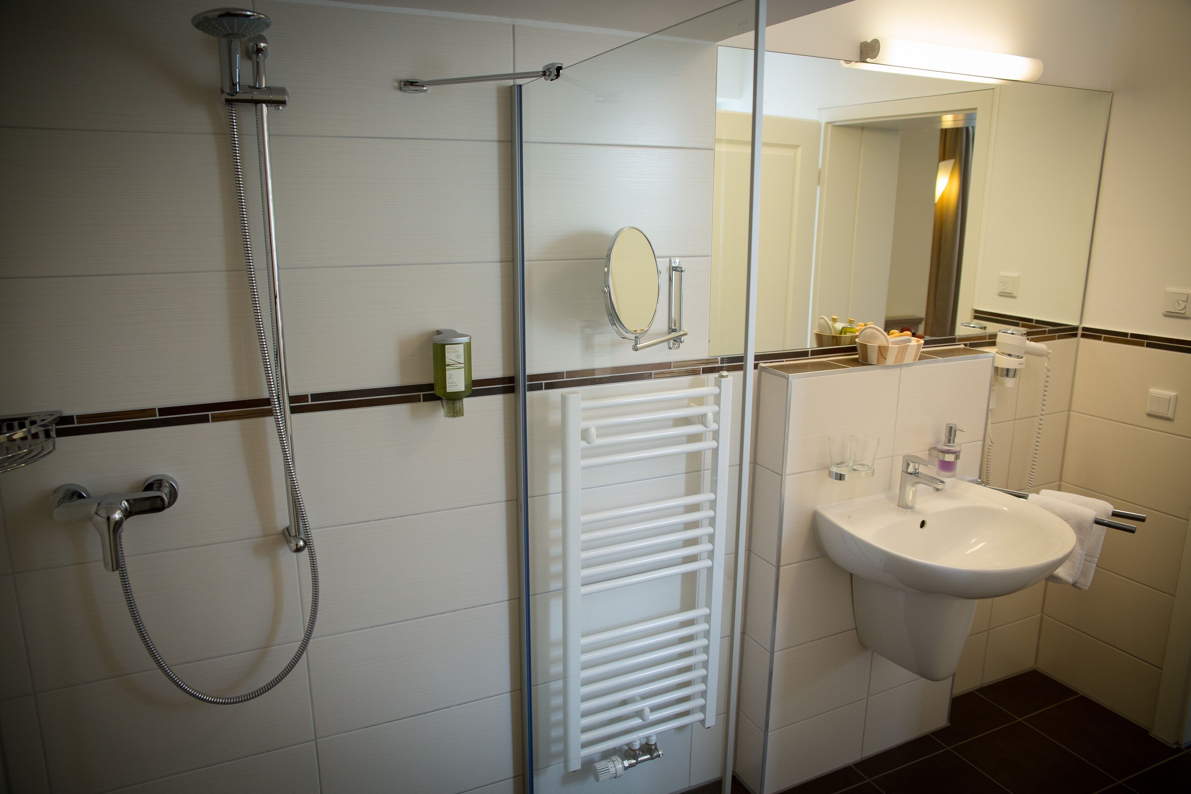 Un baño con ducha, lavamanos, toallero y espejo.