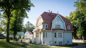 A large, two-story house with a red-tiled roof, surrounded by well-maintained lawns and trees. - Villa Ingeborg (Fürstenberg-Havel)