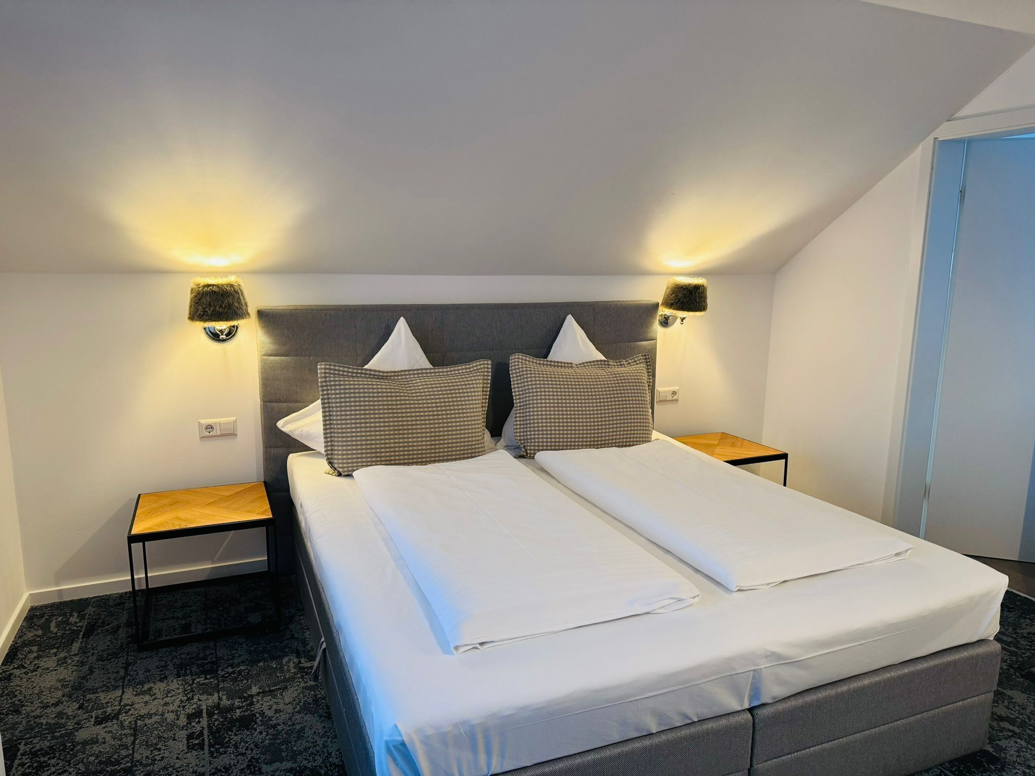 A double bed with a grey headboard and two bedside tables, each with a lamp.
