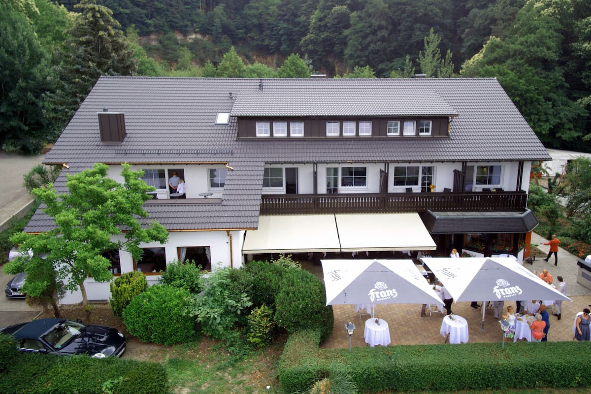 A two-story building with a flat roof, large windows, and a balcony. There are outdoor umbrellas and tables set up for an event.