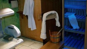 A sauna room with wooden benches, a wooden door, and a towel rack. - Hotel Restaurant Gerold (Paderborn)