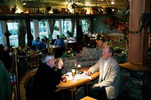 A cozy restaurant with brick walls, wooden tables, and hanging plants. - Hotel Restaurant Gerold (Paderborn)