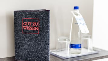 A dark grey book with red text on a tray with a bottle and glasses.