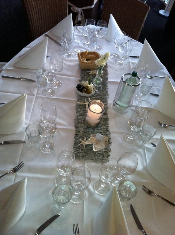 Una mesa lista para una comida, con copas de vino, una vela y una botella de agua.