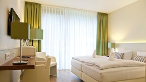 A hotel room with a bed, a desk with a lamp, a chair, and a TV. - Golfhotel Gut Winterbrock (Rheine)