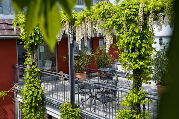 A balcony with a metal railing, potted plants, and outdoor furniture.