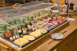 A buffet with various dairy products, cheeses, and meats.