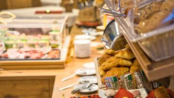 A buffet with various food items including meats, fruits, and pastries.