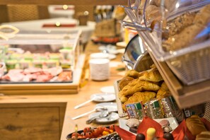 A buffet with various food items including meats, fruits, and pastries.