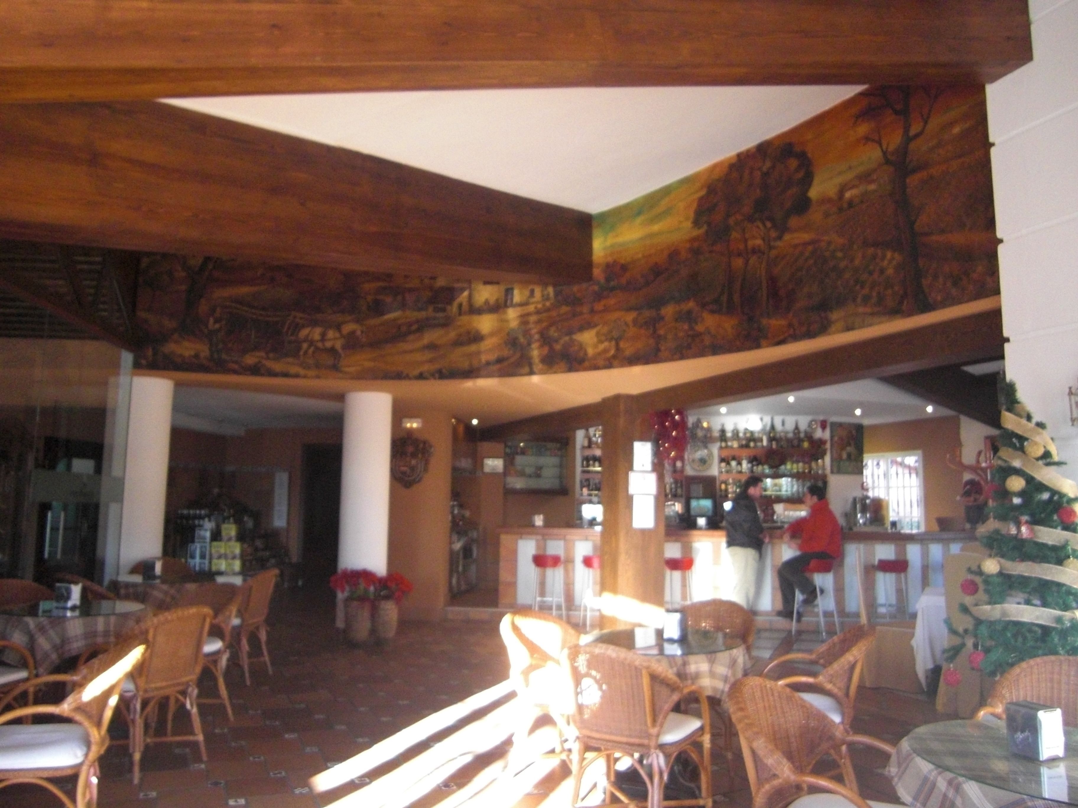 Amplio espacio interior con muebles de mimbre, una barra y un árbol de Navidad.