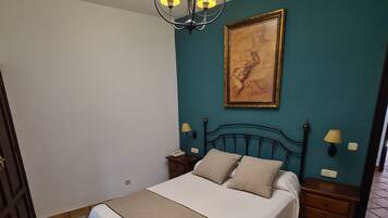 Un dormitorio con una cama, una araña, un cuadro y suelo de baldosas.