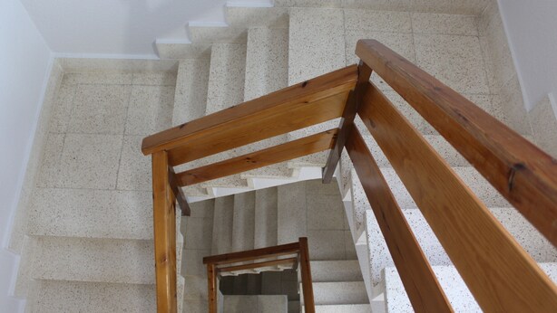 Una escalera con barandilla de madera y vista al piso inferior.