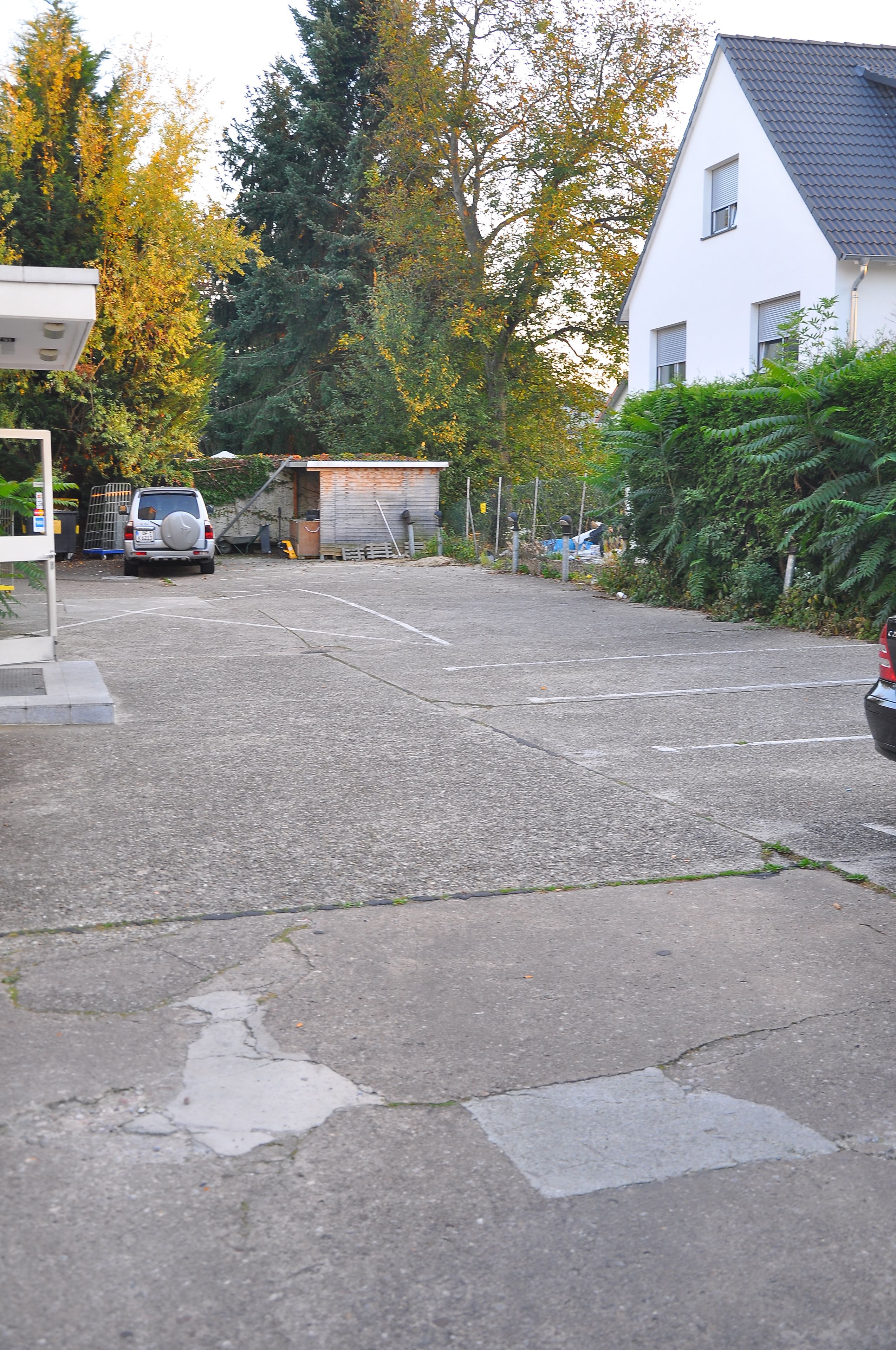 A parking lot with a white building and trees in the background.