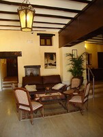 A cozy living room with a brown sofa, striped chairs, a coffee table, and a hanging lantern.
