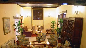 A cozy living room with patterned armchairs, a sofa, and a coffee table. There are potted plants and a wooden cabinet. - Nuevo Arlanza (Covarrubias)