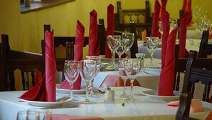 A dining table set with red napkins, wine glasses, and plates, indicating a formal dining setting. - Nuevo Arlanza (Covarrubias)