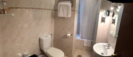 A bathroom with a toilet, a sink, a shower curtain, and a towel rack.