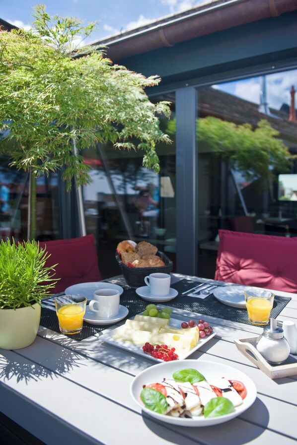 Un área de comedor al aire libre con una mesa dispuesta para el desayuno, incluyendo pan, fruta y una bebida.