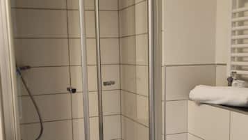 Une salle de bain moderne avec une douche à parois de verre, des toilettes blanches et un meuble-lavabo avec un miroir.